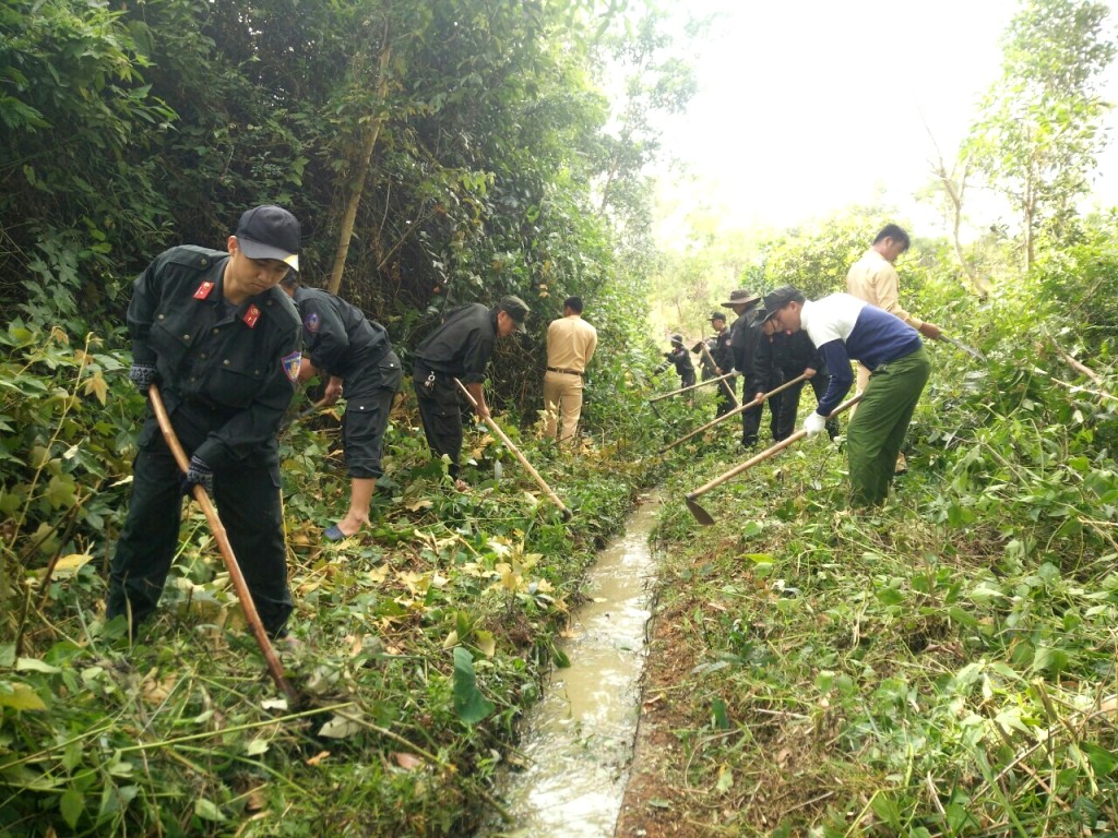 Cảnh sát Cơ động giúp nhân dân xã Cư Bông nạo vét kênh mương. Ảnh: Công An