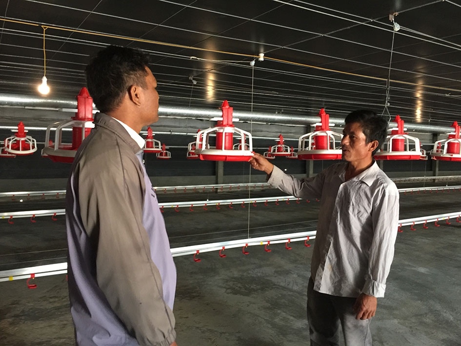 Anh Nguyễn Văn Hữu (phải) giới thiệu với cán bộ Hội Nông dân xã Cuôr Đăng về hệ thống máng ăn tự động của trang trại.