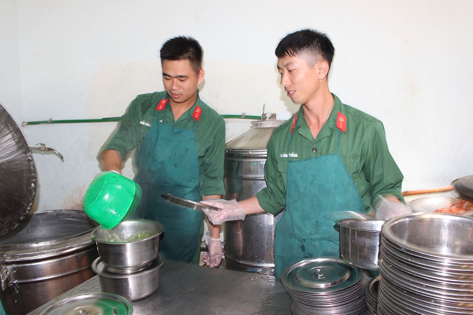 Hạ sĩ Bùi Ngọc Thắng (phải) cùng đồng đội chuẩn bị bữa ăn cho bộ đội.  