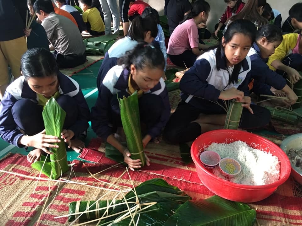 Các em học sinh đang gói bánh tét.