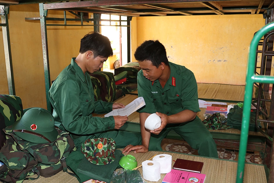 Tiểu đội trưởng hướng dẫn chiến sĩ mới kiểm tra tư trang, xếp đặt ba lô trong ngày đầu về đơn vị. 