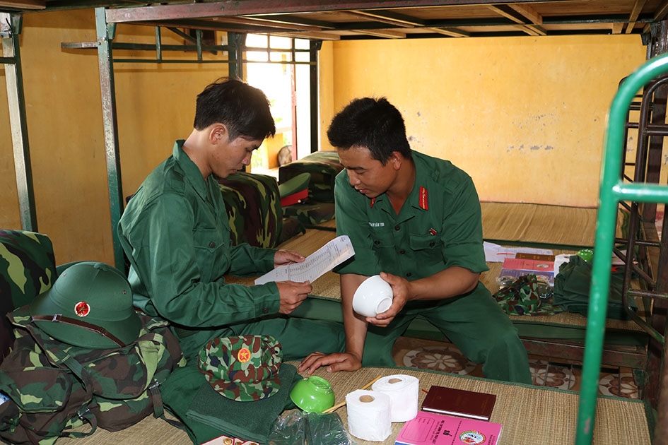 Tiểu đội trưởng hướng dẫn chiến sĩ mới kiểm tra tư trang, xếp đặt ba lô trong ngày đầu về đơn vị. 