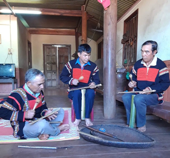Anh Y Vân Mlô (giữa) Đội trưởng đội chiêng Kram ở buôn Drah 2, xã Cư Né được các nghệ nhân hướng dẫn cách đánh chiêng. 