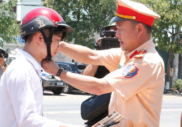 Cán bộ Phòng CSGT (Công an tỉnh) tặng mũ bảo hiểm cho học sinh tại thị trấn Ea Knốp (huyện Ea Kar).