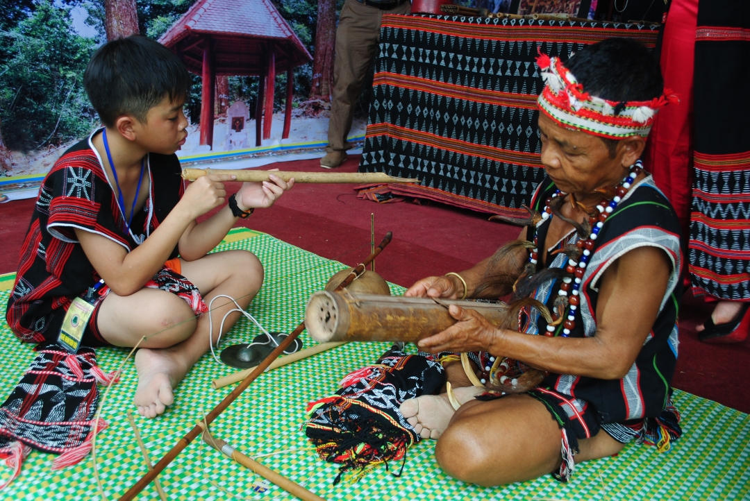 Nghệ nhân Bh’ling Argưnl (bên phải) truyền dạy đàn Gơrưna cho lớp trẻ Cơ Tu.   