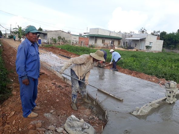 Ông Y Luận Byă (bên trái) giám sát việc làm đường giao thông nông thôn tại buôn Ea Ga, xã Cư Ni.   