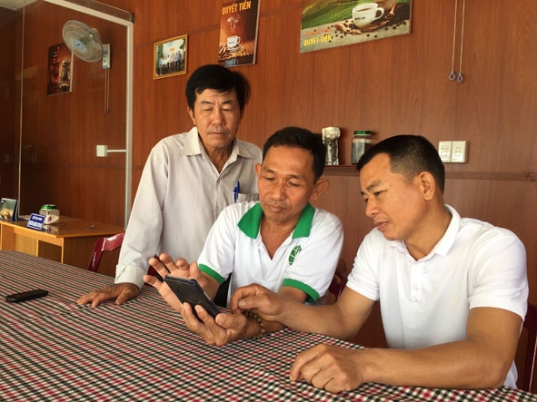 Anh Trương Hoàng Trung (giữa) giới thiệu với cán bộ, hội viên nông dân về hệ thống tưới nước tự động của gia đình qua điện thoại.