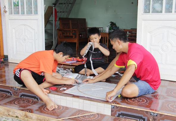 Anh Phương Minh Nhuận cùng hai con làm diều từ nan tre và giấy báo cũ. 