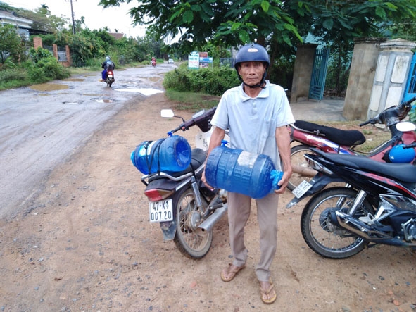 Ông Bùi Văn Thái đi lấy nước về để dùng.