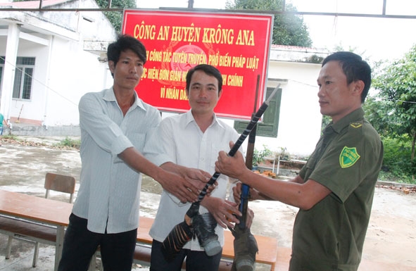 Anh Lày Văn Long (giữa), buôn Krông (xã Dur Kmăl) giao nộp súng cho Công an viên xã Dur Kmăl. 
