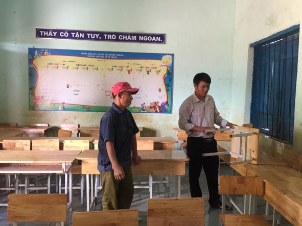 Thầy Mai  Văn Chinh, Hiệu trưởng Trường  Tiểu học Lý Tự Trọng  (bên phải) kiểm tra  bàn ghế  tại một  lớp học. 