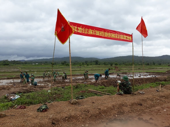 Cán bộ, chiến sĩ LLVT huyện Buôn Đôn giúp dân sản xuất tại xã Krông Na. 