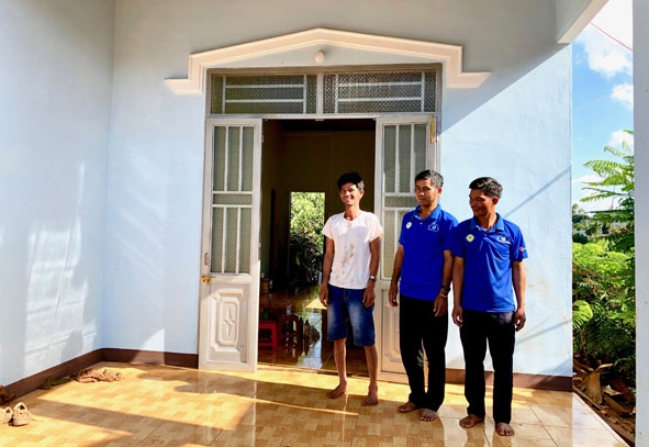Anh Ksơr Y Niết (bìa trái) phấn khởi bên ngôi nhà mới. 