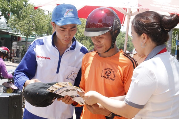 Đại diện Head Honda Trương Hòa Lợi phát tờ rơi cho người tham gia giao thông trên Quốc lộ 26.