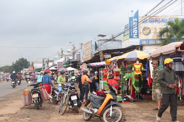 Người dân để phương tiện dọc mép Quốc lộ 27 để mua hàng tại chợ Trung Hòa (huyện Cư Kuin).