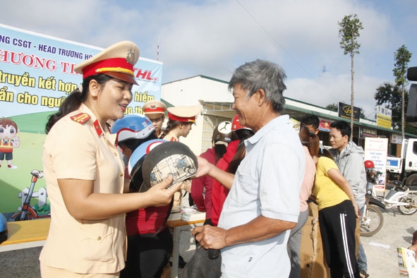 Cán bộ Phòng CSGT (Công an tỉnh) tuyên truyền Luật giao thông đường bộ và trao tặng mũ bảo hiểm cho người dân tham gia giao thông trên tuyến Quốc lộ 27 đoạn qua huyện Cư Kuin. 