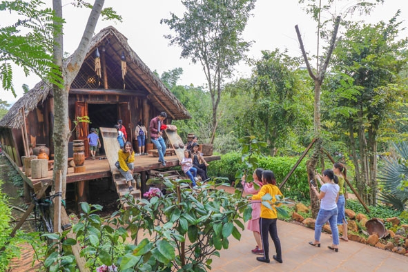 Du khách tham quan một ngôi nhà dài của người Êđê (TP. Buôn Ma Thuột).  Ảnh: H. Gia