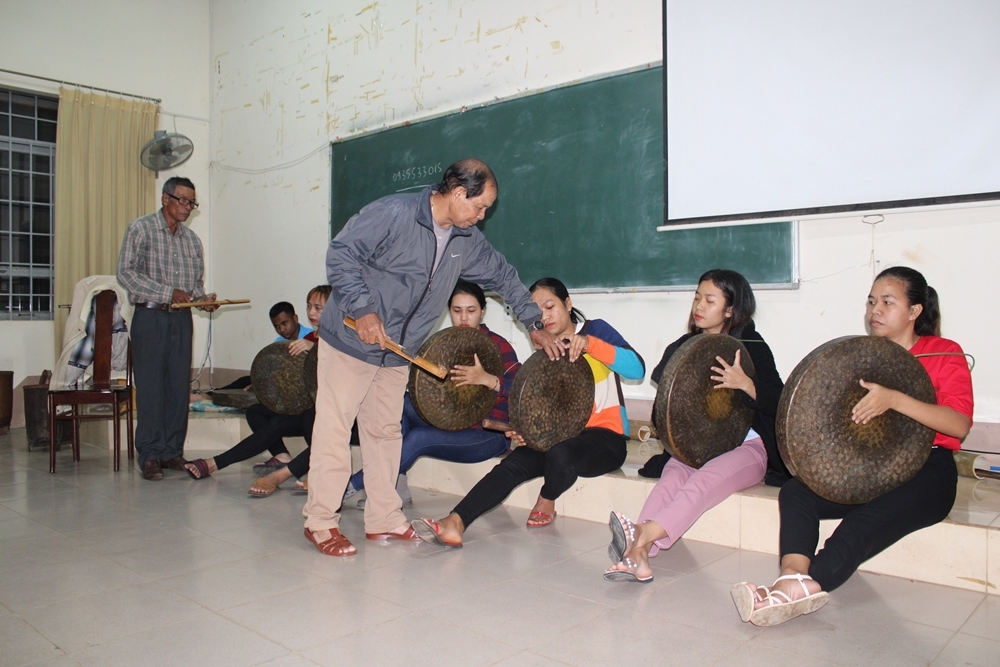 Nghệ nhân hướng dẫn cách  đánh chiêng cho  học viên  là sinh viên DTTS  của Trường Đại học  Tây Nguyên. 
