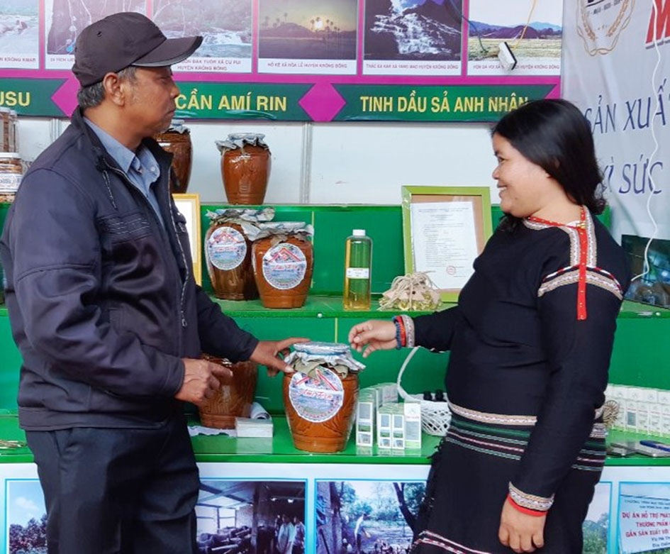 Chị H’Jih Niê  giới thiệu  sản phẩm  rượu cần  Amí Rin  tại Hội chợ  nông nghiệp  và sản phẩm OCOP khu vực Tây Nguyên  tại Đắk Lắk  năm 2019.