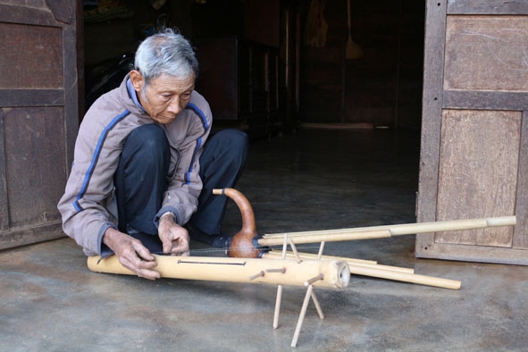 Ông Y Ki Mlô say sưa gảy nhạc trên cây đàn goong. 