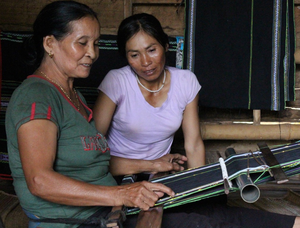 Bà H’Dleh Byă (bên trái) chỉ dạy cách dệt thổ cẩm cho con gái.