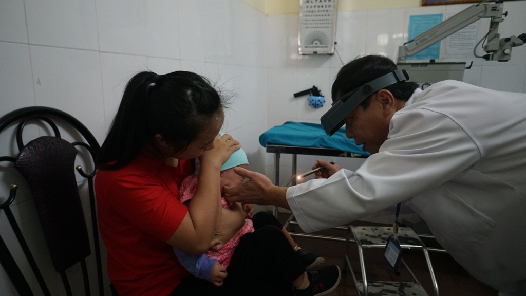 Bác sĩ Lê Văn Thanh Bình khám cho bệnh nhi viêm kết mạc tại Bệnh viện Mắt tỉnh.  Ảnh: Q. Nhật