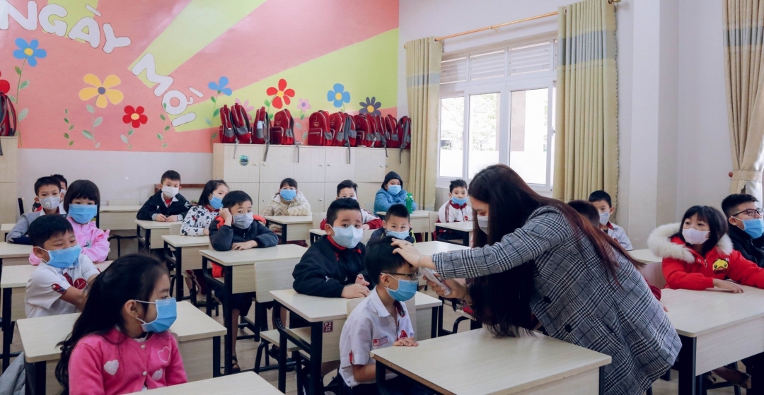 Kiểm tra thân nhiệt cho các em học sinh tại lớp học.