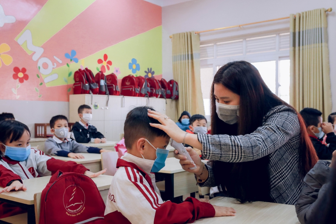 Nhân viên Trường Tiểu học, THCS & THPT Hoàng Việt kiểm tra thân nhiệt cho các em học sinh. Ảnh: C.Xin