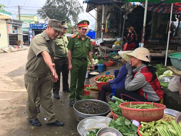 Anh Huỳnh Tấn Lợi (bìa trái) phối hợp với lực lượng chức năng tuyên truyền các hộ  không buôn bán dưới lòng đường.  