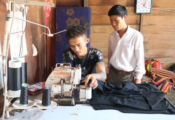 Anh Bùi Đức Sơn (bên trái) đã có việc làm thường xuyên từ nghề may gia công.