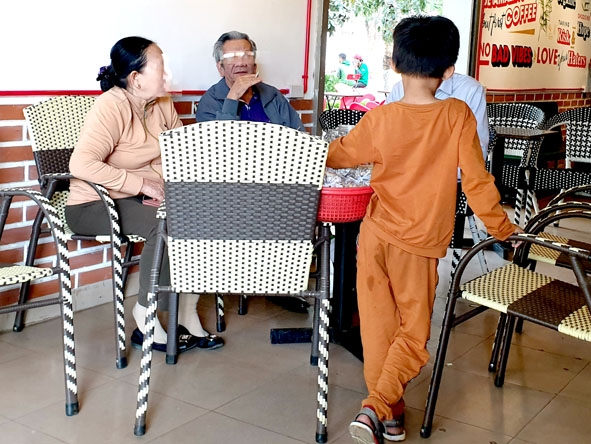 Một cậu bé bán hàng rong đứng nguyên tại bàn để chèo kéo khách. 