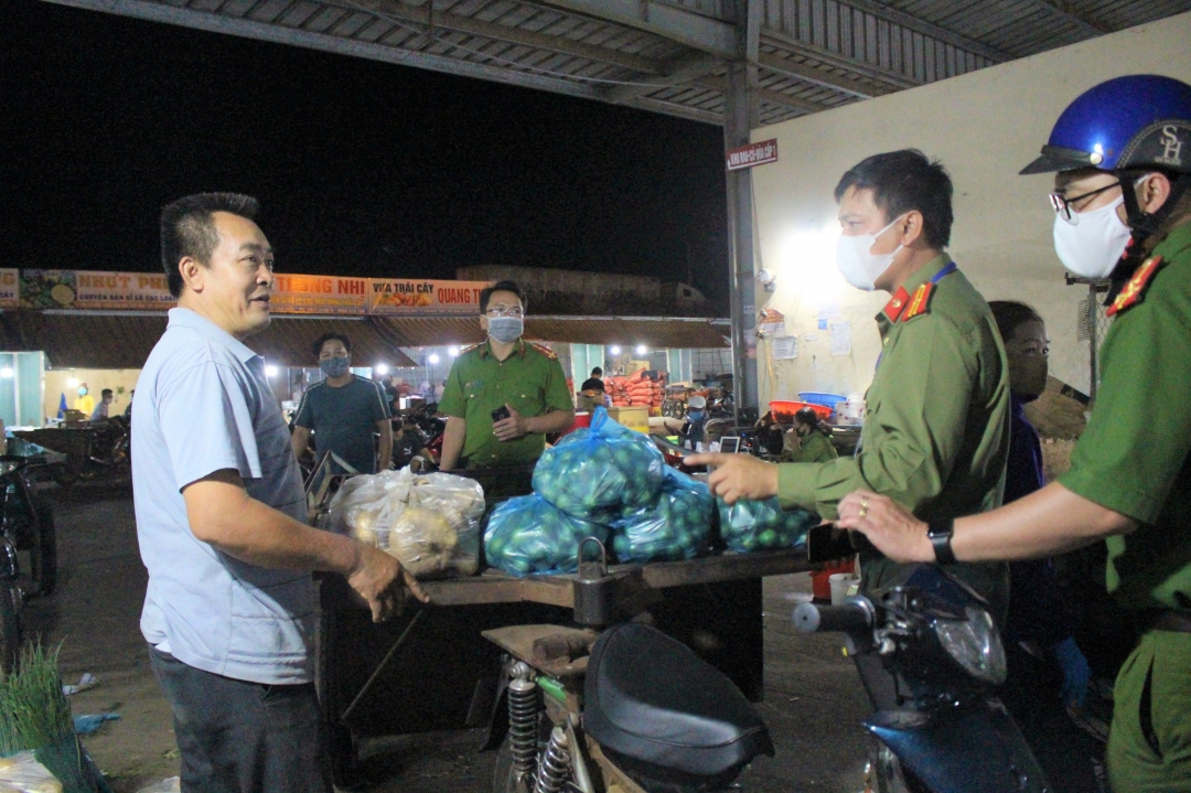 Đoàn kiểm tra nhắc nhở tiểu thương chấp hành nghiêm việc đeo khẩu trang. (Ảnh chụp tại chợ đầu mối Tân Hòa vào rạng sáng ngày 6-4) Ảnh: Thùy Linh