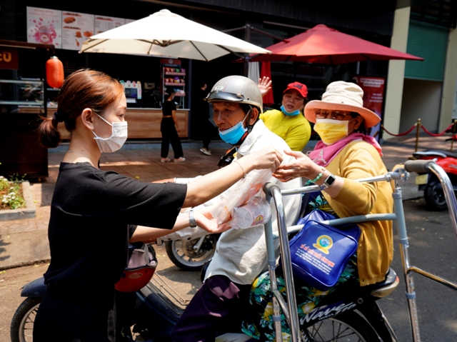 Mỗi buổi trưa 2 điểm bán của quán cà phê ở số 8- Hai Bà Trưng và 32 Quang Trung lại phát hơn 100 phần quà gồm một ổ bành mì thịt và một hộp mì ăn liền cho những người nghèo.Nhân viên quán cà phê ở 32 Quang Trung tặng bánh mì và hộp mì cho những người có hoàn cảnh khó khăn vào mỗi buổi trưa (ảnh chụp trưa ngày 7-4)