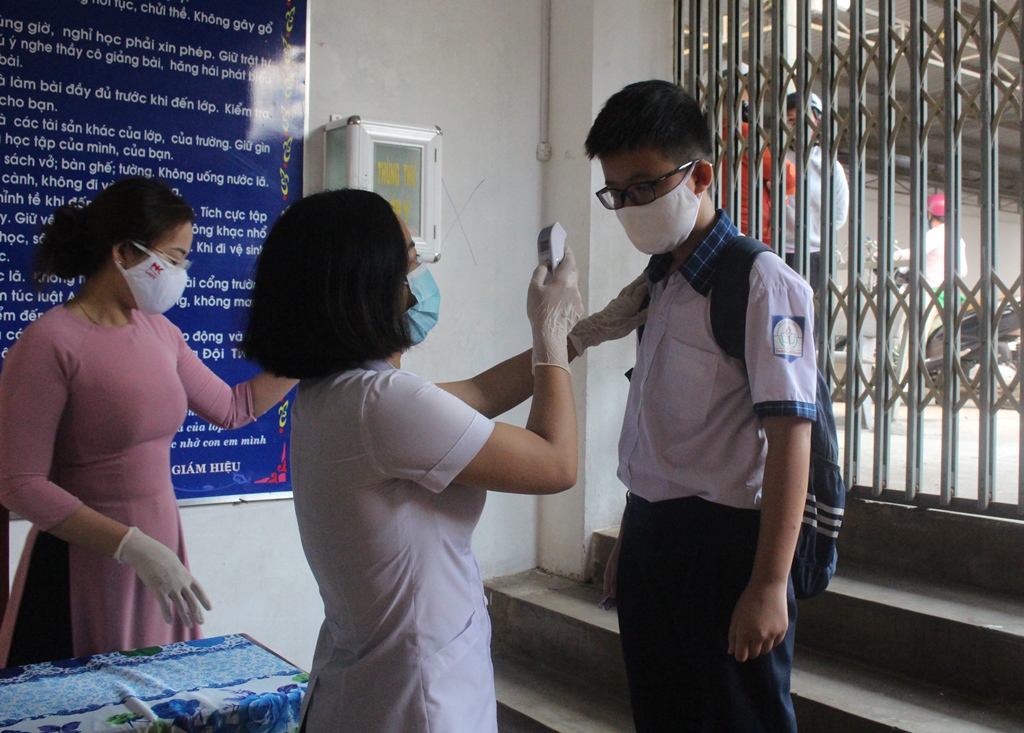 Giáo viên Trường Tiểu học Phan Chu Trinh (TP. Buôn Ma Thuột) đo thân nhiệt học sinh trước khi vào lớp.