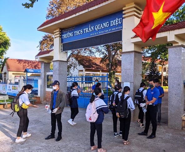 Đoàn viên thanh niên xã Hòa Thuận (TP. Buôn Ma Thuột) hướng dẫn học sinh sát khuẩn trước khi vào lớp học.   Ảnh: Anh Phương