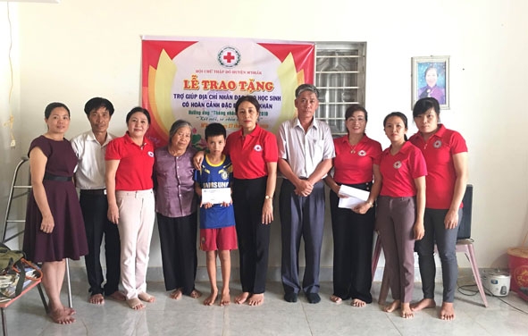 Đại diện Trung tâm Y tế huyện M'Đrắk (ở giữa) trao học bổng cho trẻ mồ côi