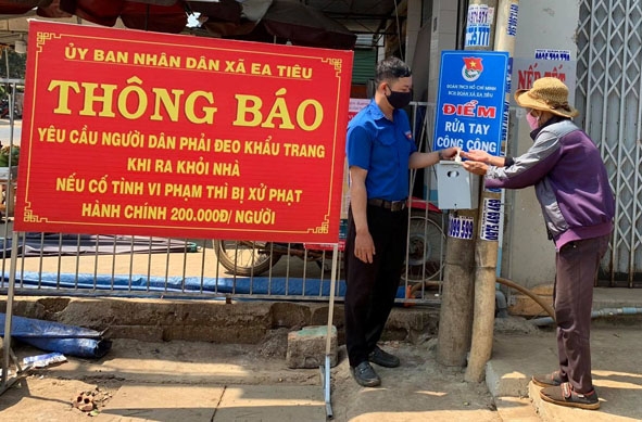 Thanh niên xã Ea Tiêu hướng dẫn người dân sát khuẩn đúng cách phòng, chống dịch bệnh Covid-19.