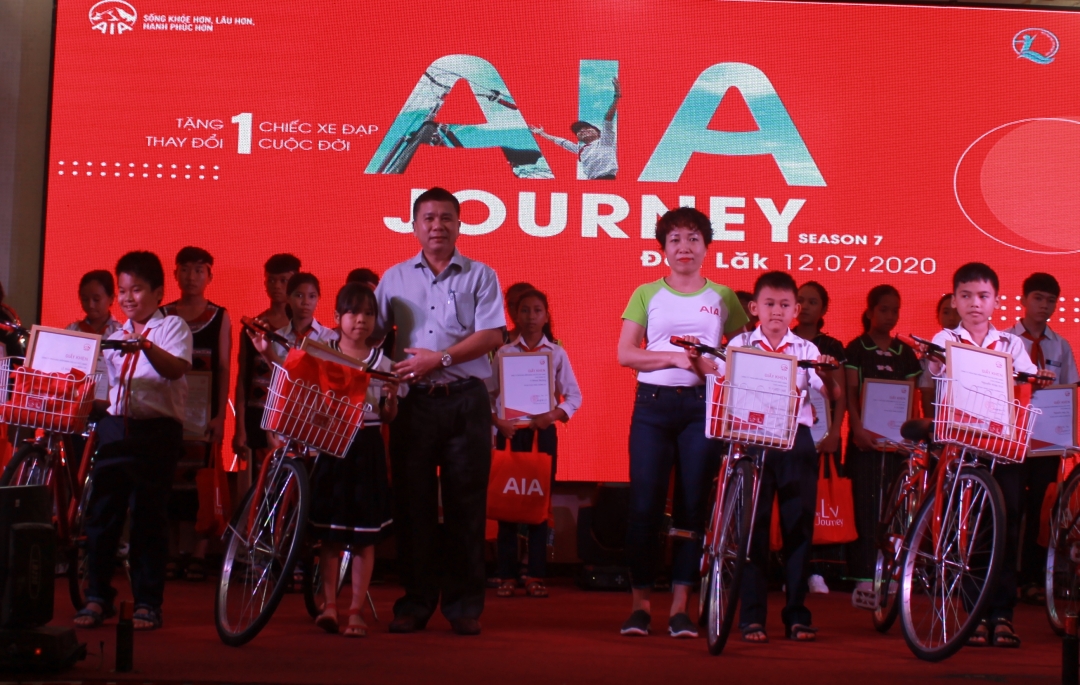 Giám đốc Quỹ Bảo trợ trẻ em tỉnh Lâm Đình Nhiên và đại diện Công ty TNHH Bảo hiểm nhân thọ AIA tặng xe đạp và quà cho các học sinh có hoàn cảnh khó khăn. 