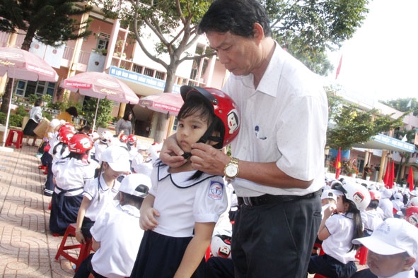 Ông Bùi Văn Ngọc, Chánh Văn phòng Ban An toàn giao thông tỉnh trao mũ bảo hiểm cho học sinh Trường Tiểu học Nguyễn Công Trứ (TP. Buôn Ma Thuột).  