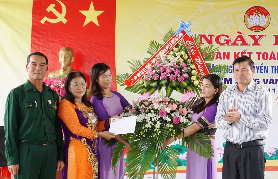 Bí thư Huyện ủy Krông Bông Đỗ Quốc Hương (bên phải) tặng hoa và quà cho Ban công tác Mặt trận thôn 11.