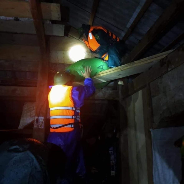 Bộ đội, dân quân hỗ trợ người dân kê đặt tài sản, thóc lúa lên cao tránh lũ.   Ảnh. Nhất Vũ