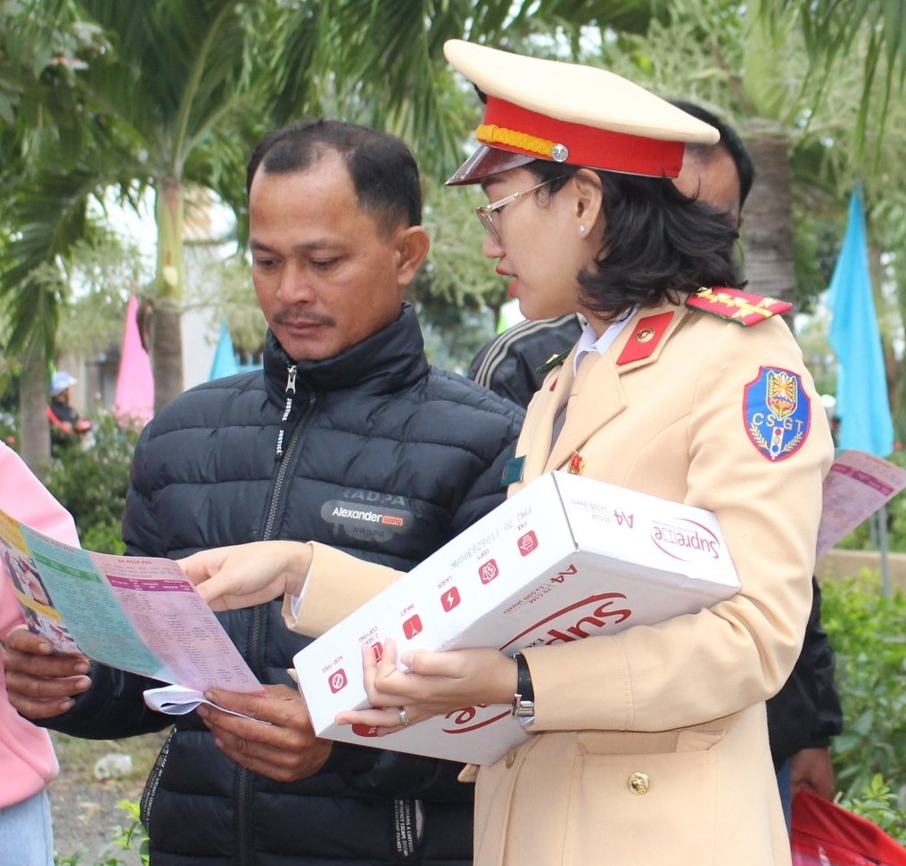 Cán bộ Phòng Cảnh sát giao thông phát tờ rơi và hướng dẫn Luật Giao thông đường bộ cho người dân xã Ea Wer.