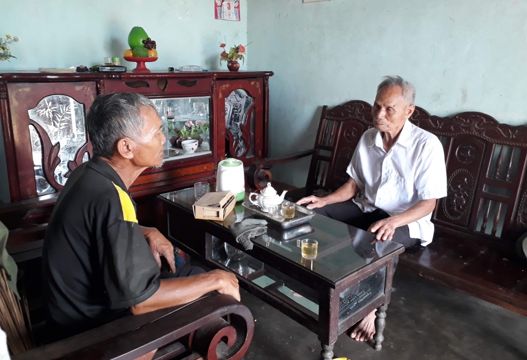 Ông Nguyễn Xuân Phức (bên phải) trao đổi với người dân về công việc của thôn. 