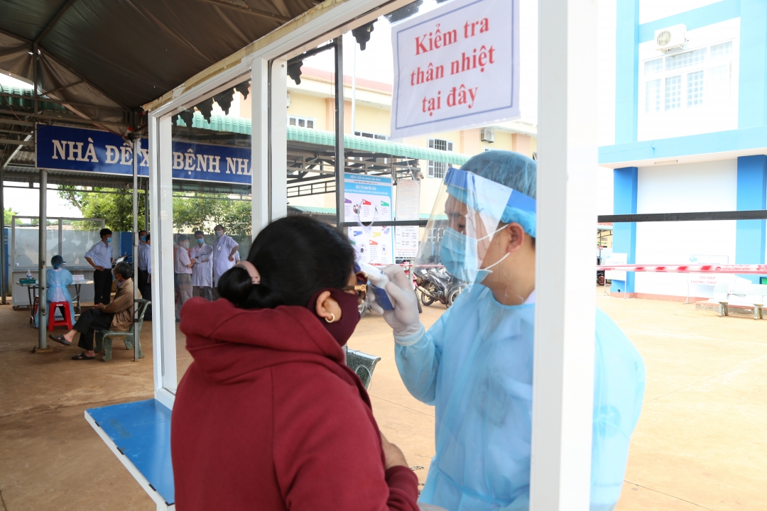 Kiểm tra thân nhiệt người dân trước khi vào thăm khám tại các cơ sở y tế.  Ảnh: Đình Thi