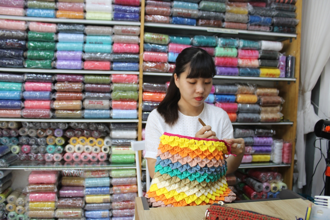 Bùi Thị Bảo Trâm đang móc túi xách  cho khách hàng.   