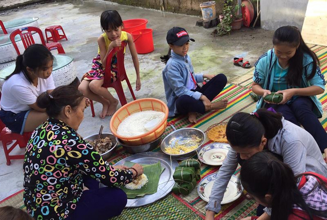 Những đứa trẻ nơi đô thị hóa học gói bánh chưng ngày Tết. Ảnh: N.Sơn