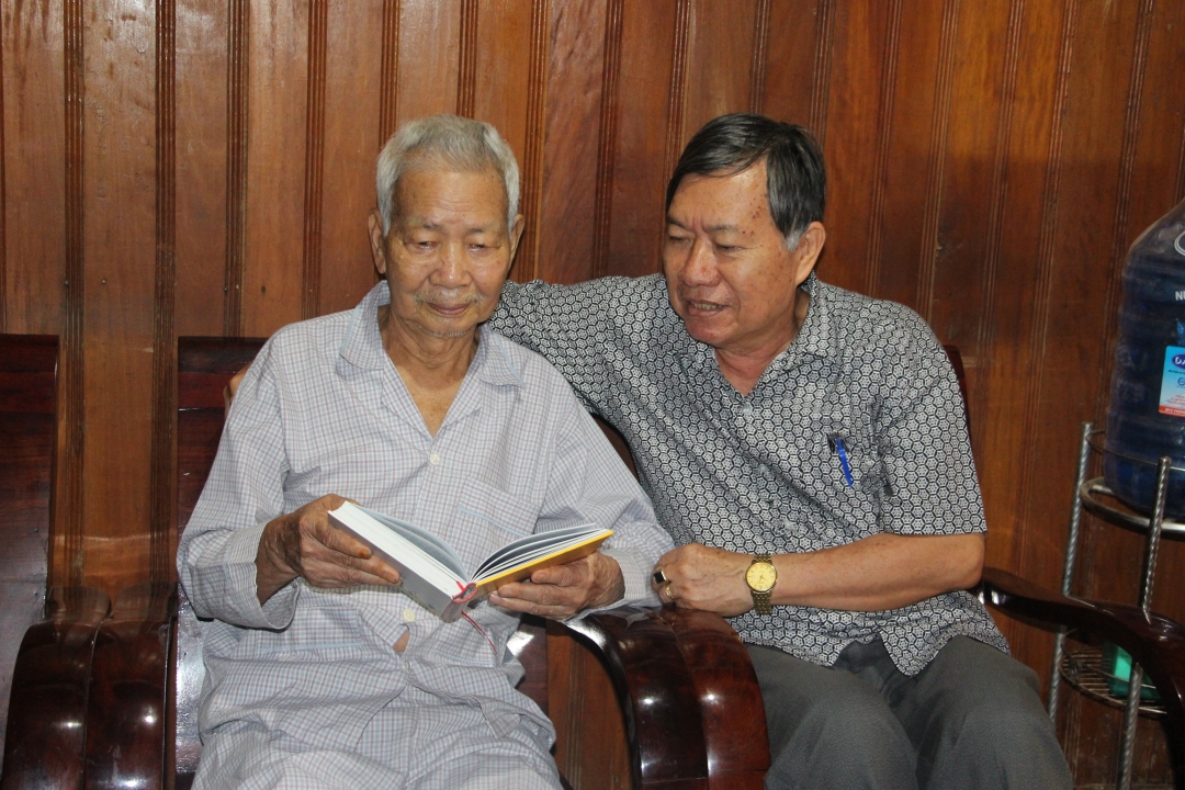 Nguyên Chủ tịch UBND huyện Ea Súp Nguyễn Công Huân (bên trái) rưng rưng khi đọc lại bức thư của Đại tướng Võ Nguyên Giáp trong Lịch sử Đảng bộ huyện Ea Súp Ảnh: