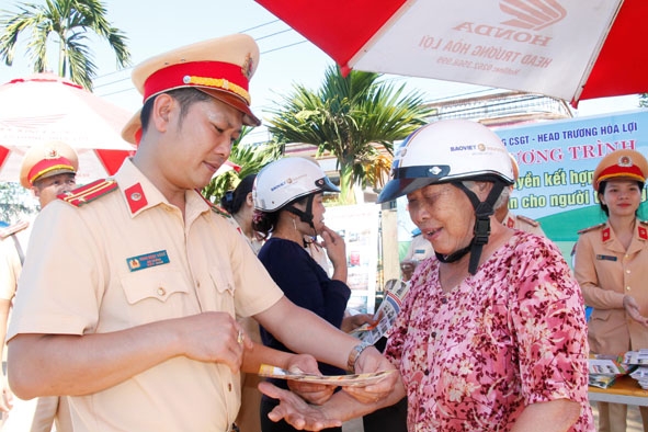 Cán bộ Phòng CSGT Công an tỉnh tuyên truyền Luật Giao thông đường bộ cho người dân dọc Quốc lộ 26 (đoạn qua huyện Krông Pắc).  Ảnh: Hoàng Tuyết