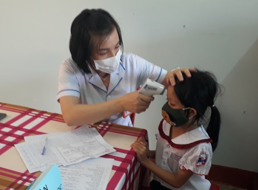 Cán bộ y tế khám sàng lọc cho học sinh trước khi tiêm chủng. 