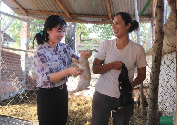 Cán bộ Hội Liên hiệp Phụ nữ xã Ea Nuôl (bên trái) thăm mô hình nuôi thỏ của hội viên, phụ nữ buôn Ea Mdhar 1A.